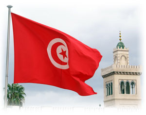 Die rot-weiße Flagge Tunesiens vor blauem Himmel im Wind.